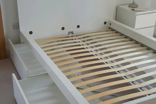 Mover using tools to dismantle a wardrobe during a residential house move.